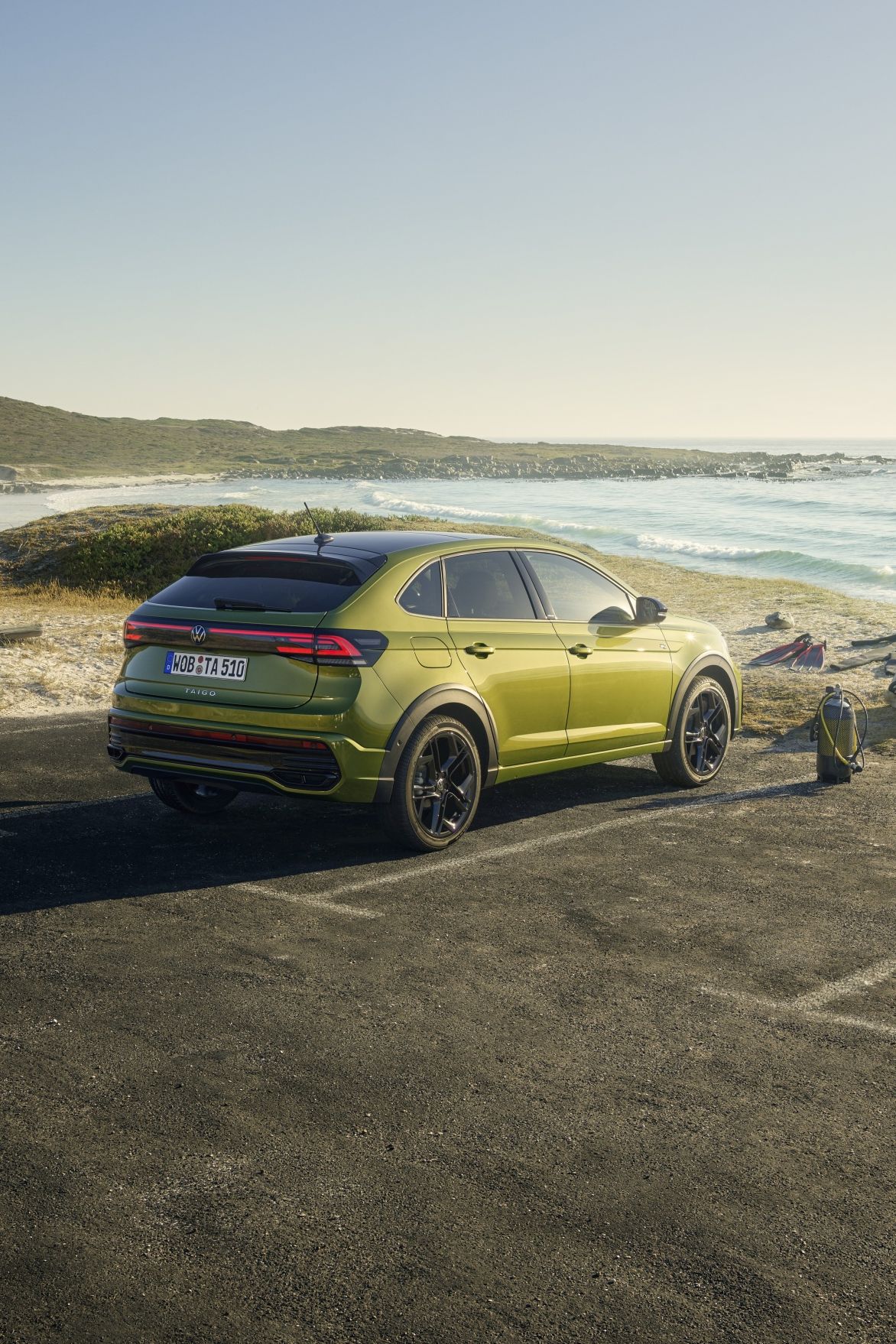 Volkswagen Taigo паркиран до плажа с изглед към морето и планините