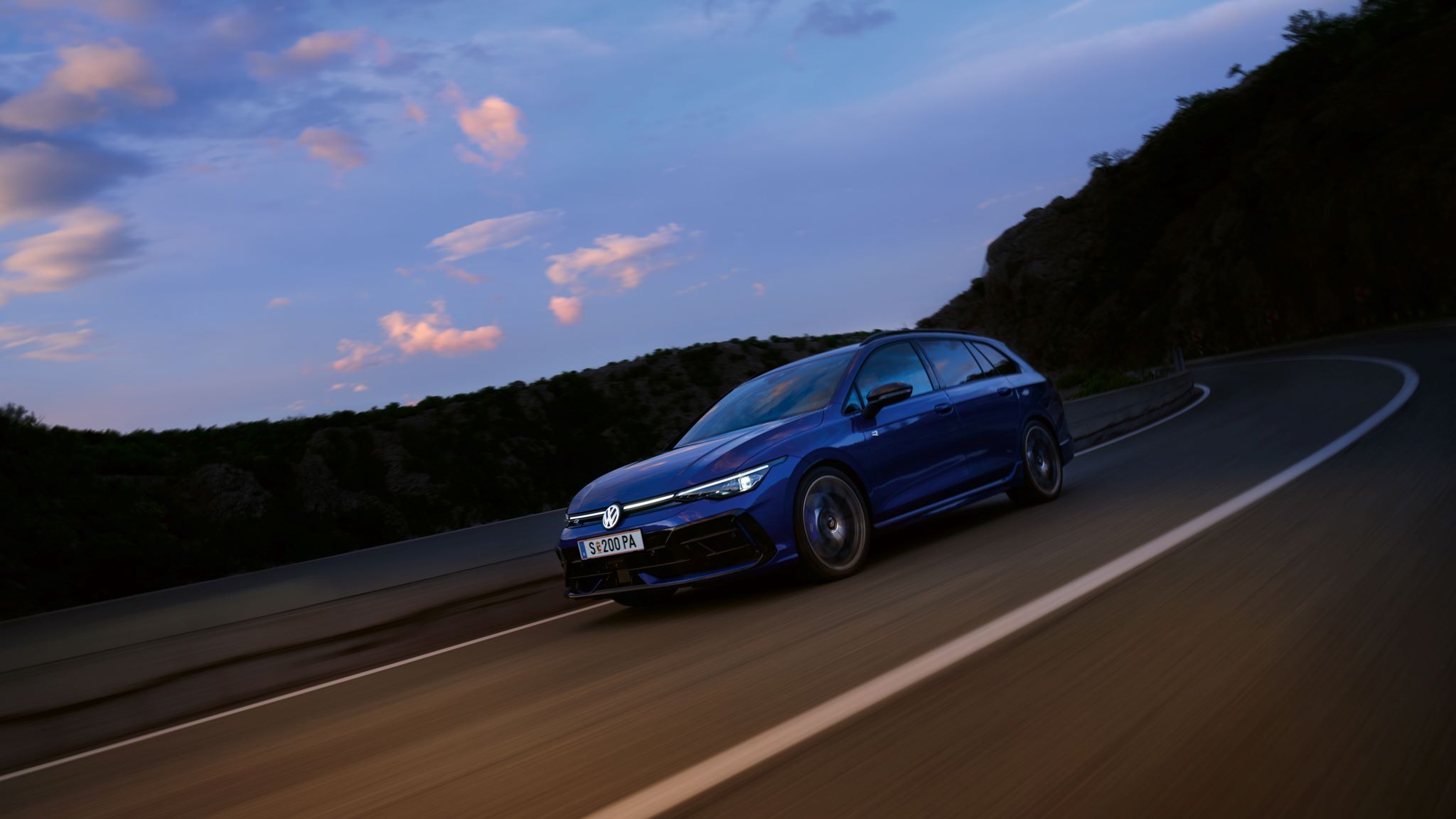 Син Volkswagen Golf Variant R в движение по планински завой привечер
