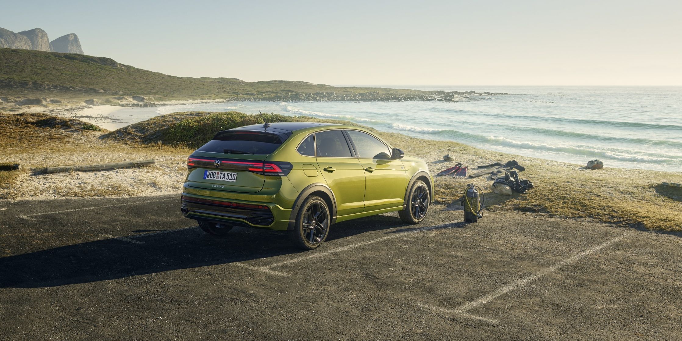 Volkswagen Taigo паркиран до плажа с изглед към морето и планините