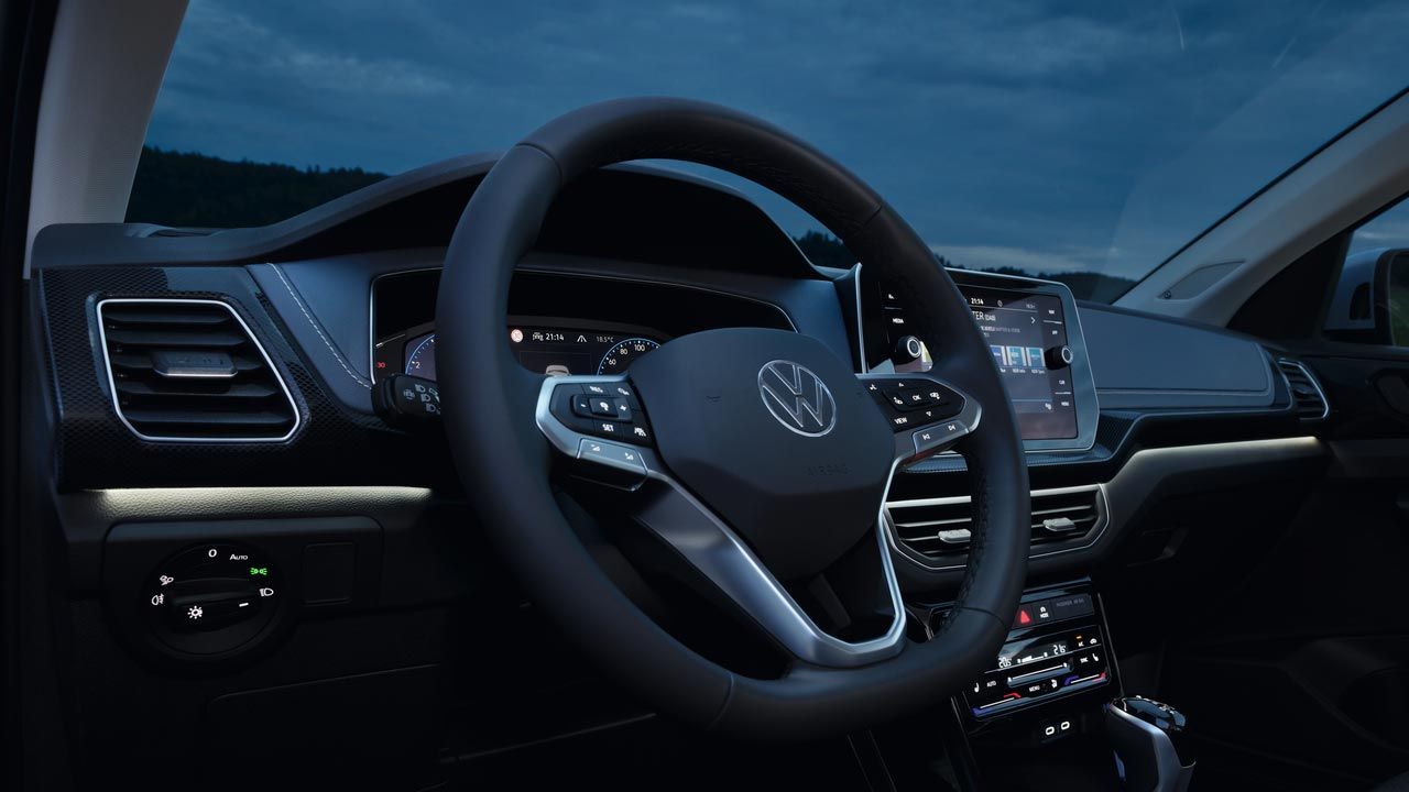 Подробен нощен изглед на арматурното табло на VW T-Cross с акцент върху бялото амбиентно осветление