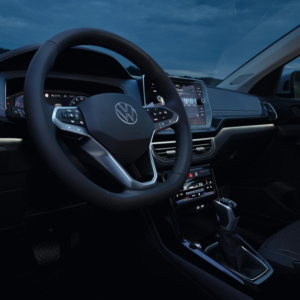 Подробен нощен изглед на арматурното табло на VW T-Cross с акцент върху бялото амбиентно осветление