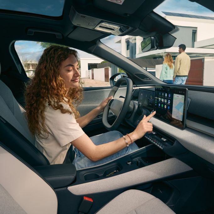 Млада жена седи на шофьорското място на VW ID. Cross и управлява инфотейнмънт системата.
