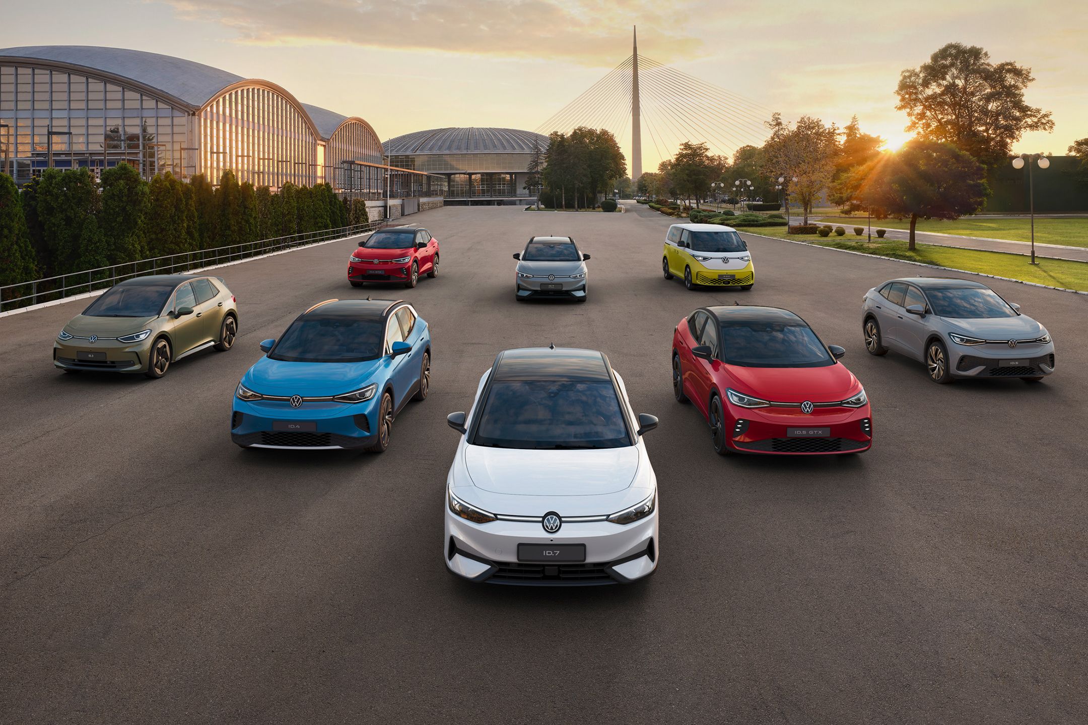 Група най-новите модели електрически автомобили на Volkswagen, паркирани в редица пред модерни сгради и мост. Снимката е направена в ранна сутрин при изгрев.