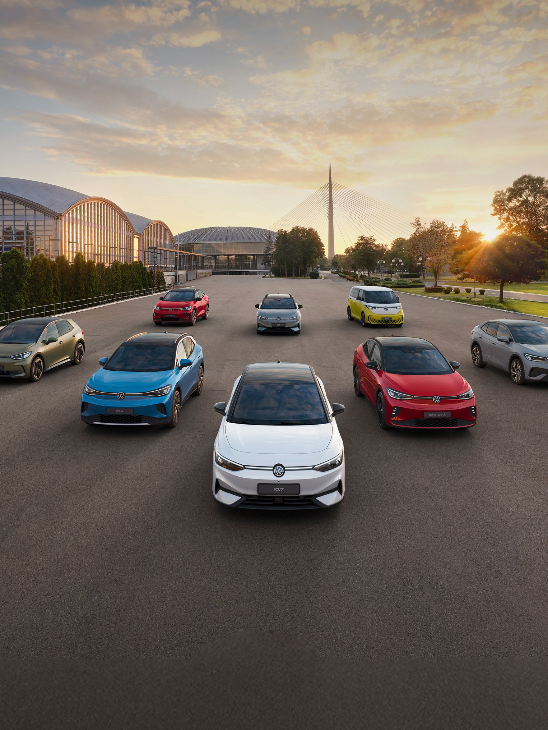 Група най-новите модели електрически автомобили на Volkswagen, паркирани в редица пред модерни сгради и мост. Снимката е направена в ранна сутрин при изгрев.
