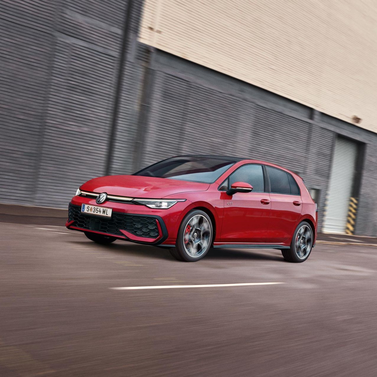 Червен Volkswagen Golf GTI в движение пред индустриална сграда