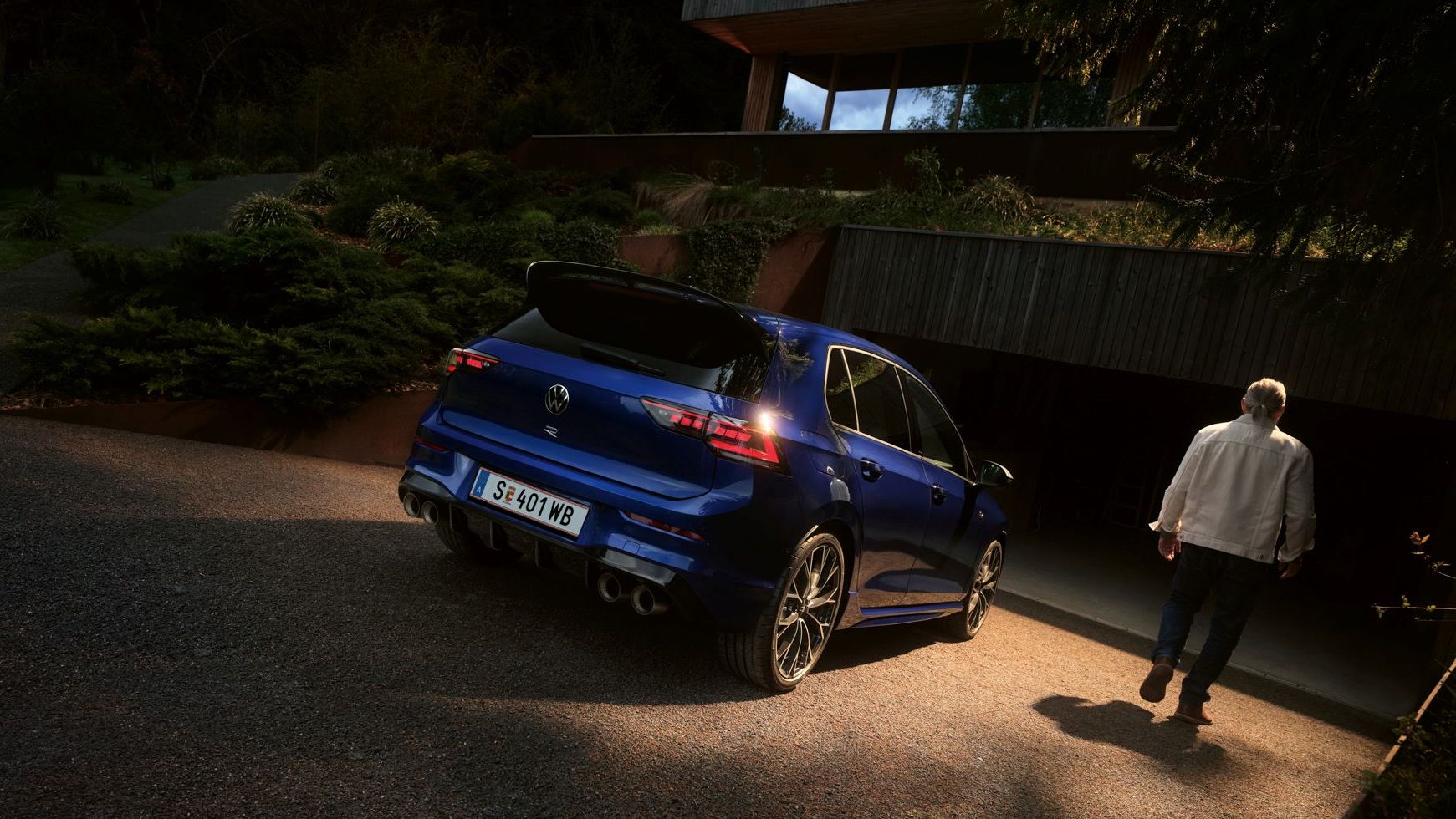 Golf R befindet sich geparkt vor einer Garage, daneben geht ein Mann vorbei.