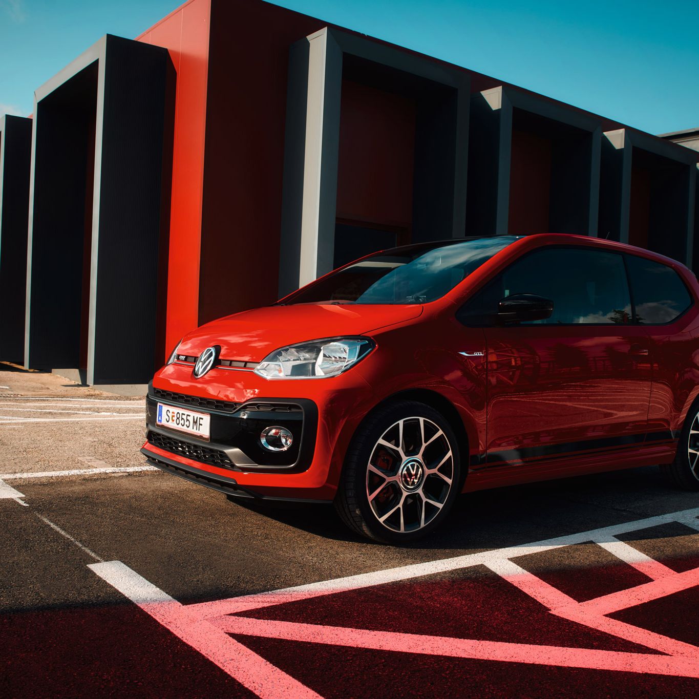 Червен Volkswagen up! GTI, паркиран в модерна градска среда с геометрични акценти