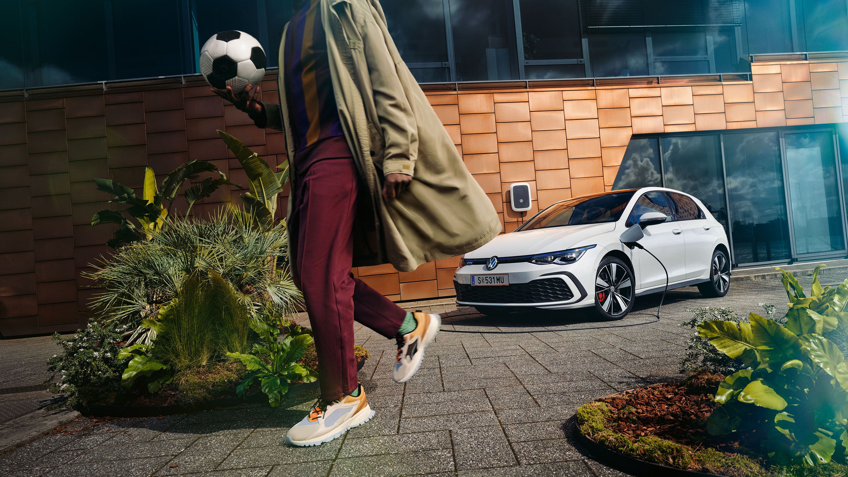 Ein ladender VW Golf GTE hinter dem Anschnitt eines Mannes, der sich grade vom Fahrzeug entfernt. 