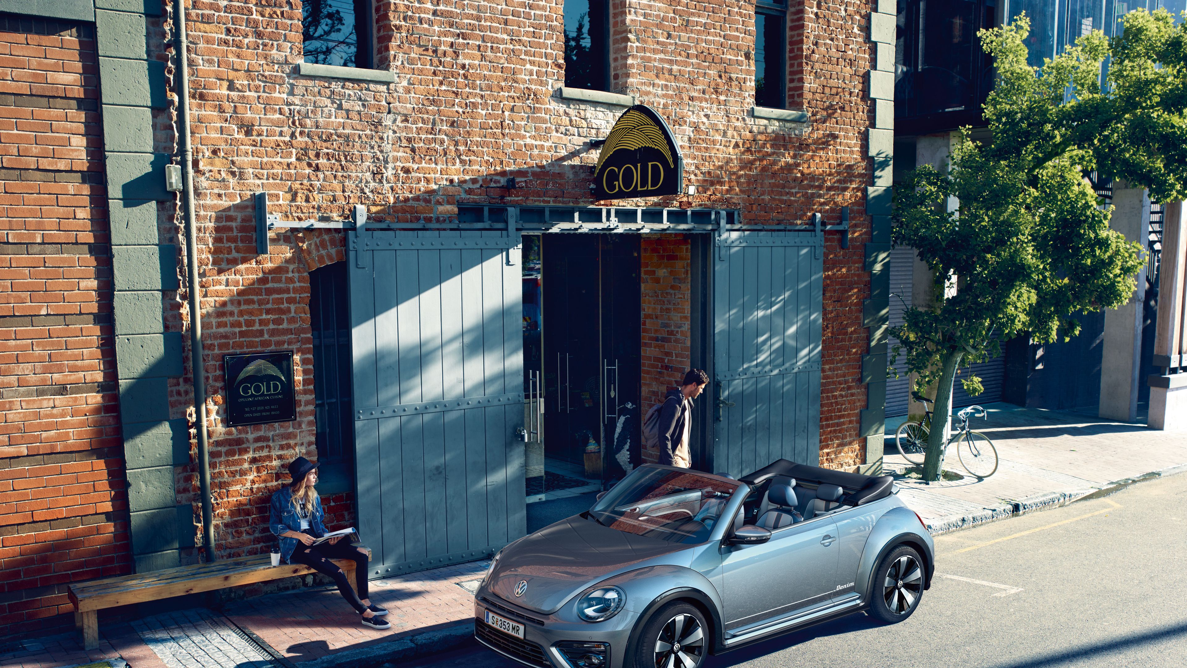Сив Volkswagen Beetle кабриолет паркиран пред тухлена сграда в градска среда