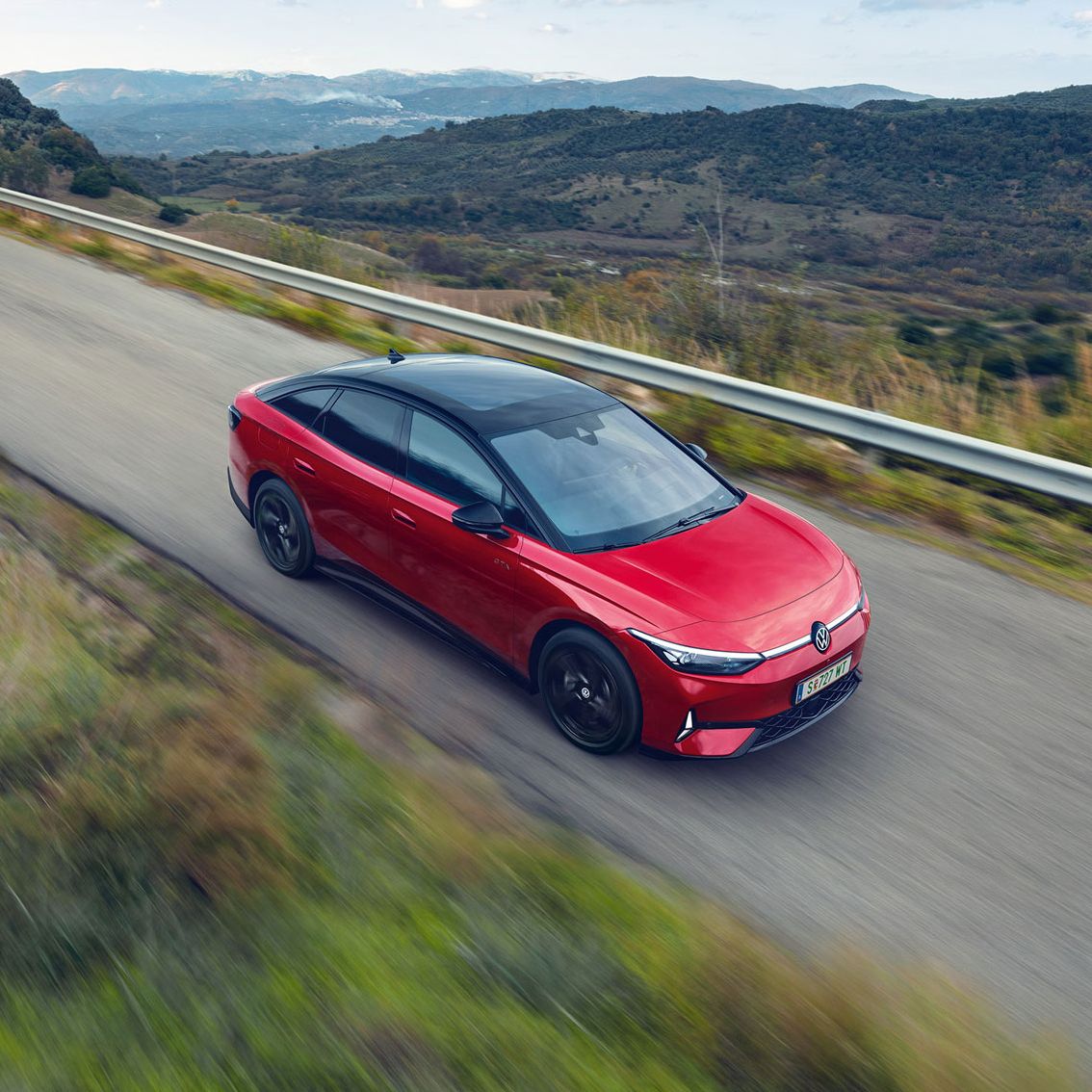 Червен Volkswagen ID.7 GTX в движение по живописен планински път