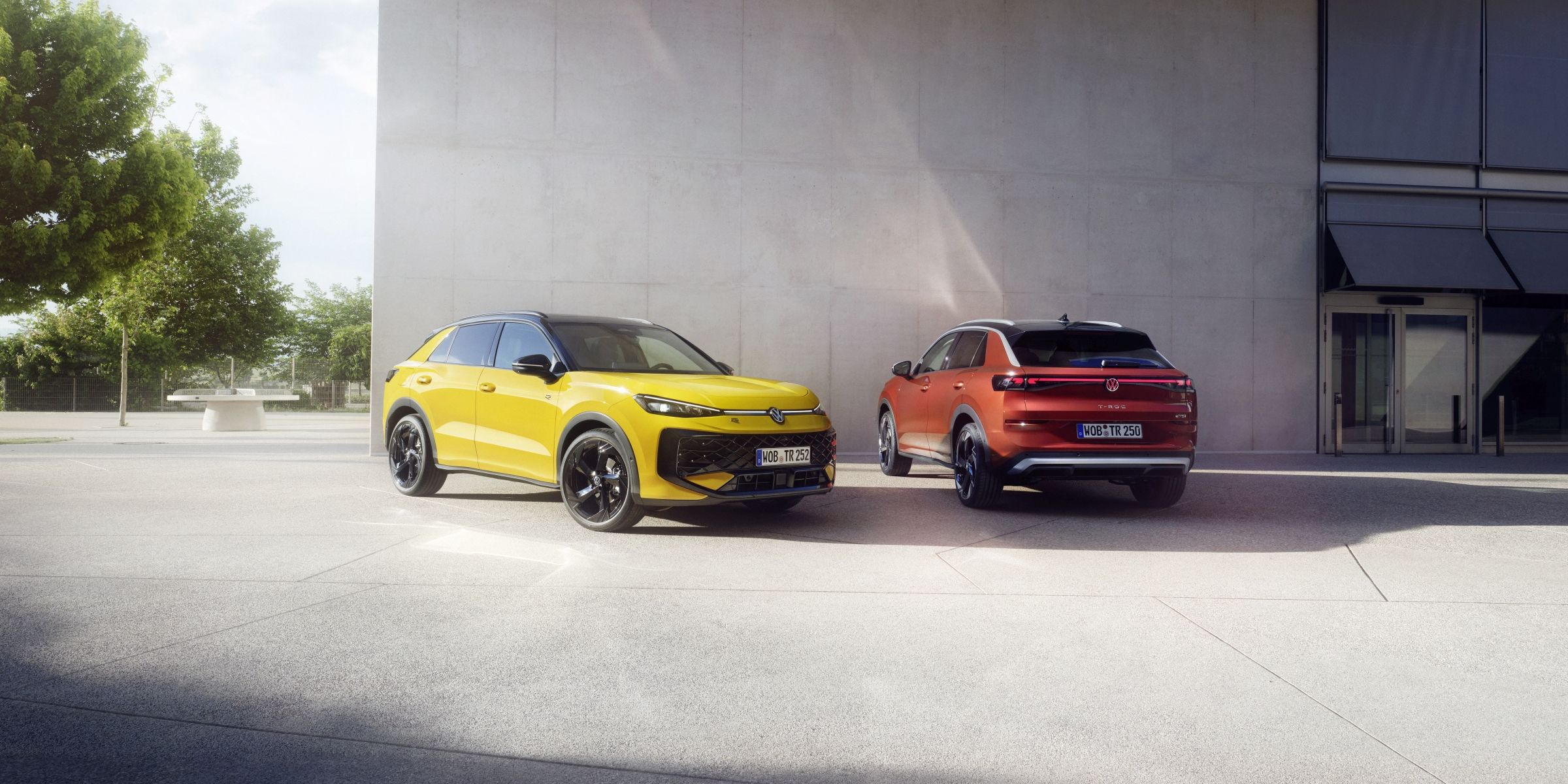 Жълт и оранжев Volkswagen T-Roc паркирани пред модерна сграда