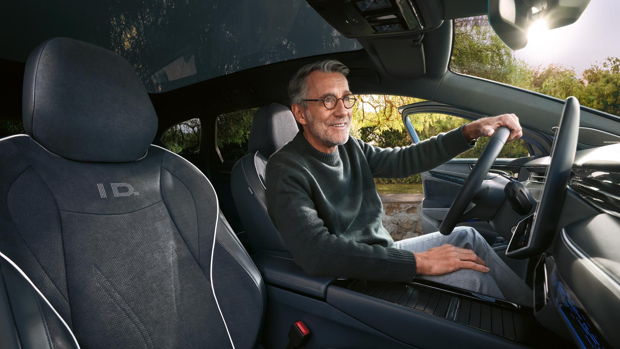 Усмихнат мъж на шофьорското място във Volkswagen ID.7 Tourer с елегантен интериор