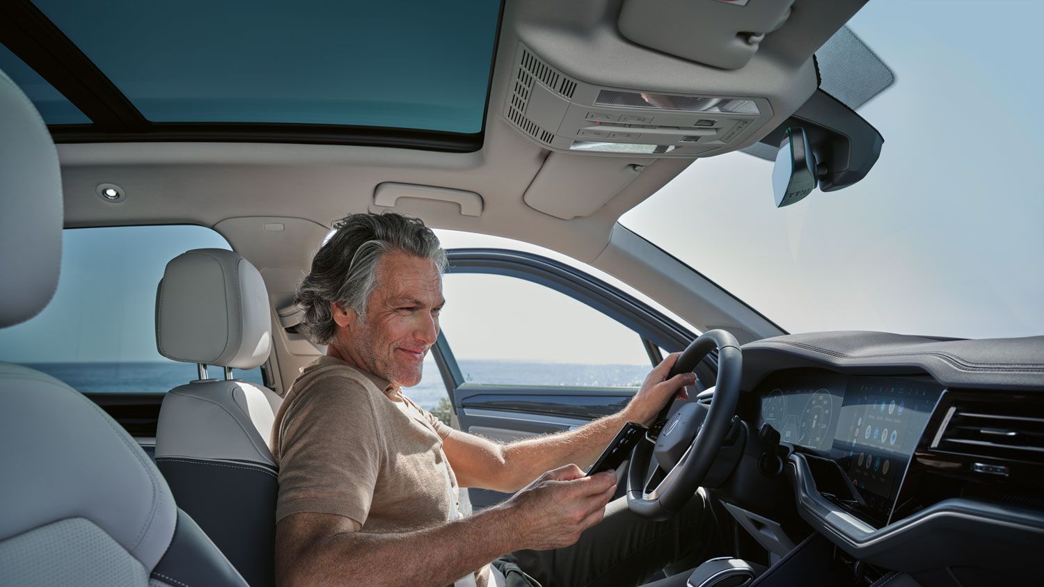 Мъж в паркиран VW Touareg Elegance свързва своя смартфон с VW Touareg Elegance чрез Wireless App Connect.