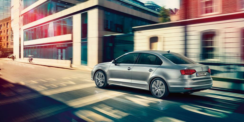 Сребрист Volkswagen Jetta в движение по градска улица