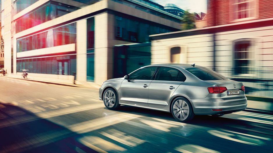 Сребрист Volkswagen Jetta в движение по градска улица