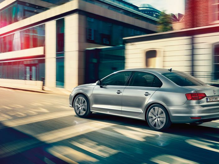 Сребрист Volkswagen Jetta в движение по градска улица