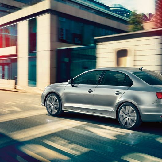 Сребрист Volkswagen Jetta в движение по градска улица