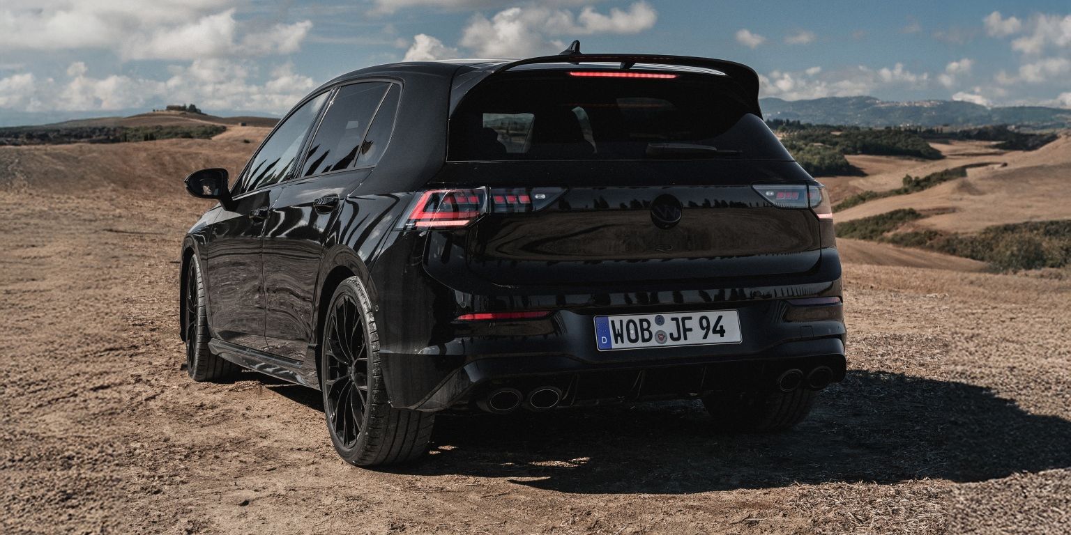 Черен Volkswagen Golf R, заснет отзад сред живописен пейзаж с хълмове и синьо небе