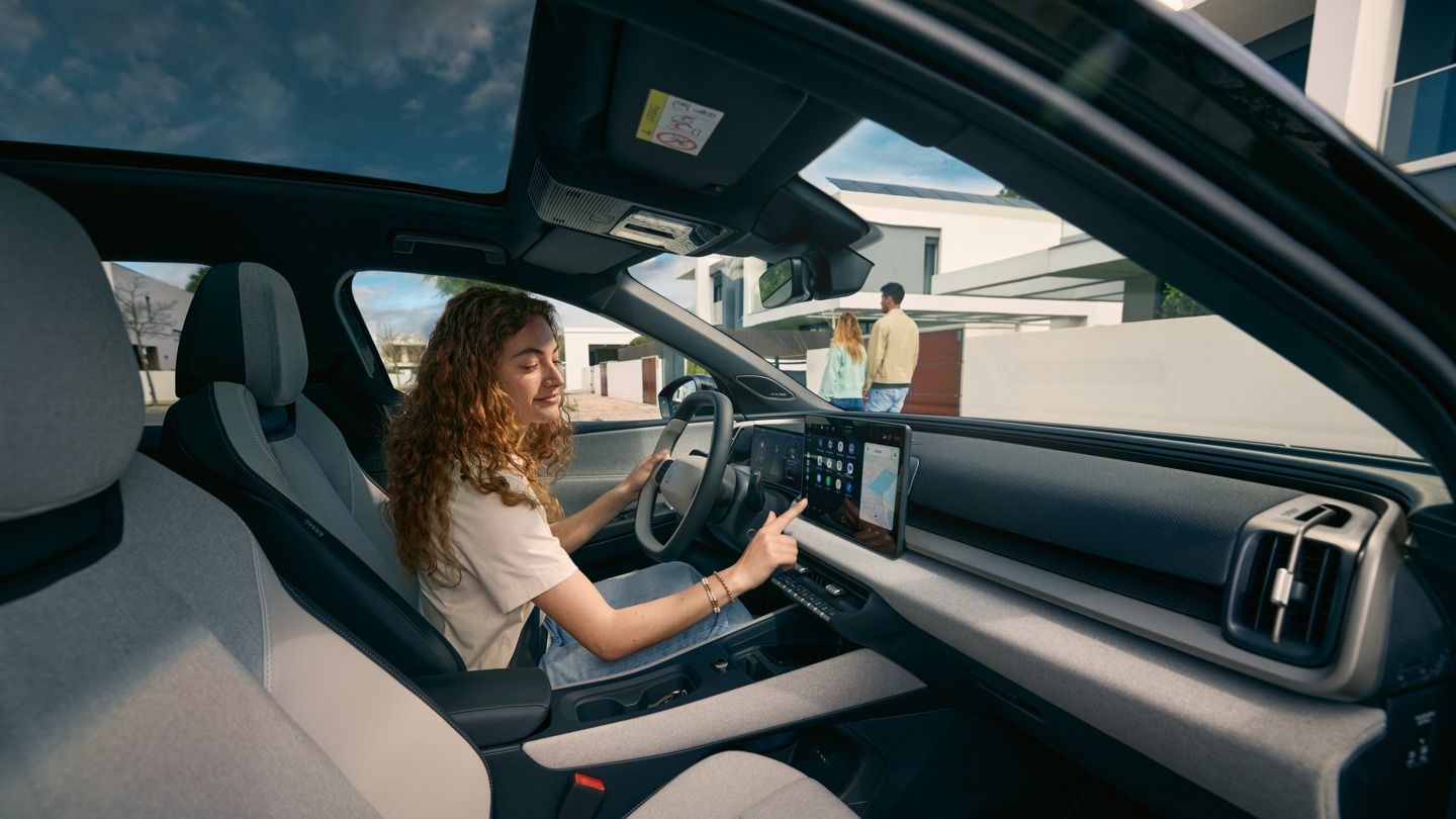 Млада жена седи на шофьорското място на VW ID. Cross и управлява инфотейнмънт системата.