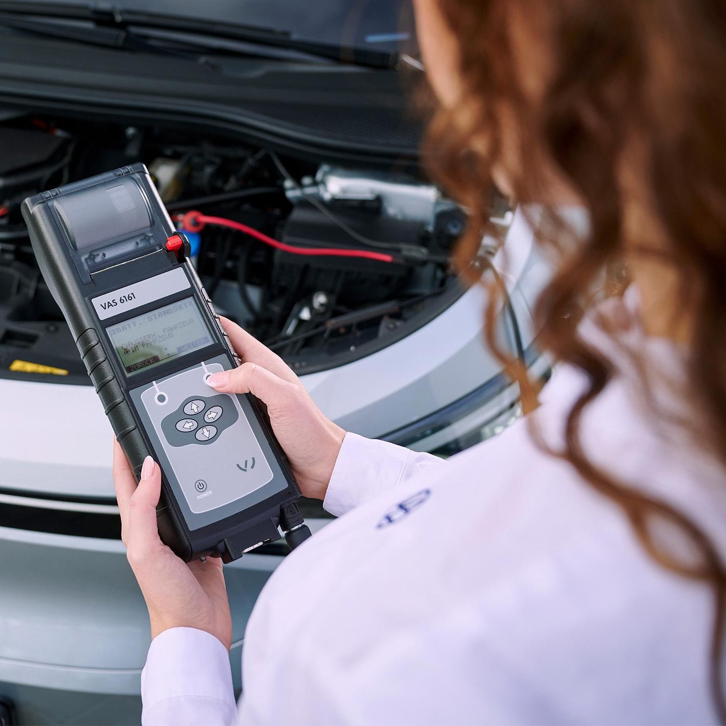 Сервизен специалист на Volkswagen извършва тест на акумулатора с диагностично устройство.