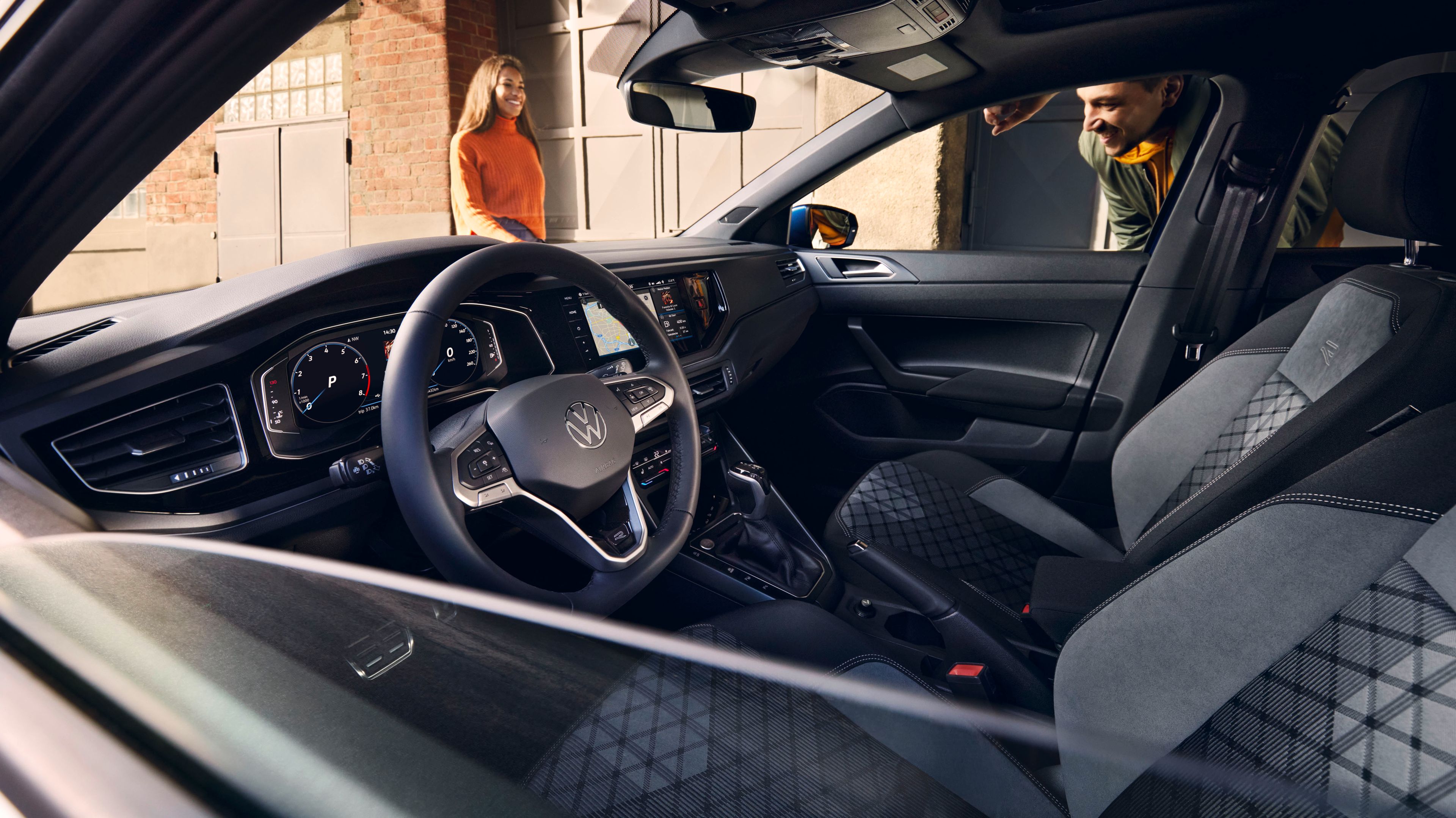 Поглед през отворен прозорец напречно към интериора на VW Polo с опционалния Digital Cockpit Pro, волан и седалки. 