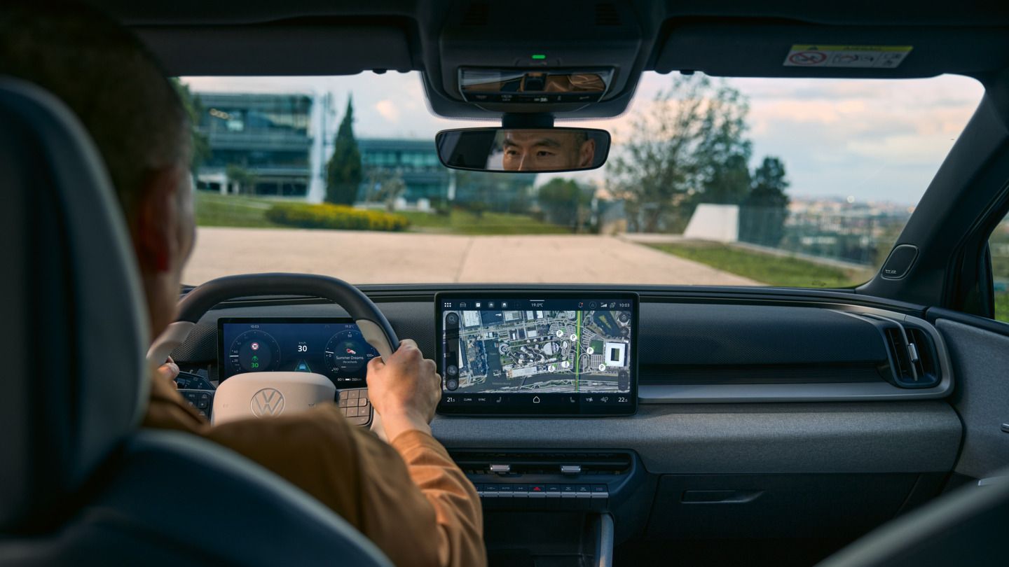 Изглед от задната седалка към кабината на водача на VW ID. Cross с активна навигация на екрана на инфотейнмънт.