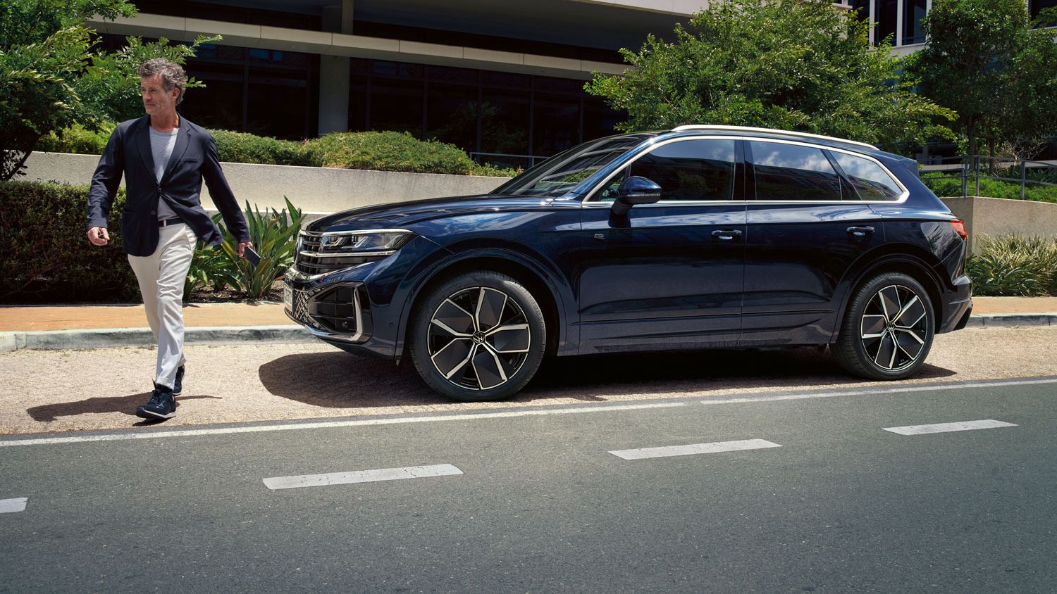 Мъж пресича улицата пред паркиран VW Touareg R-Line.