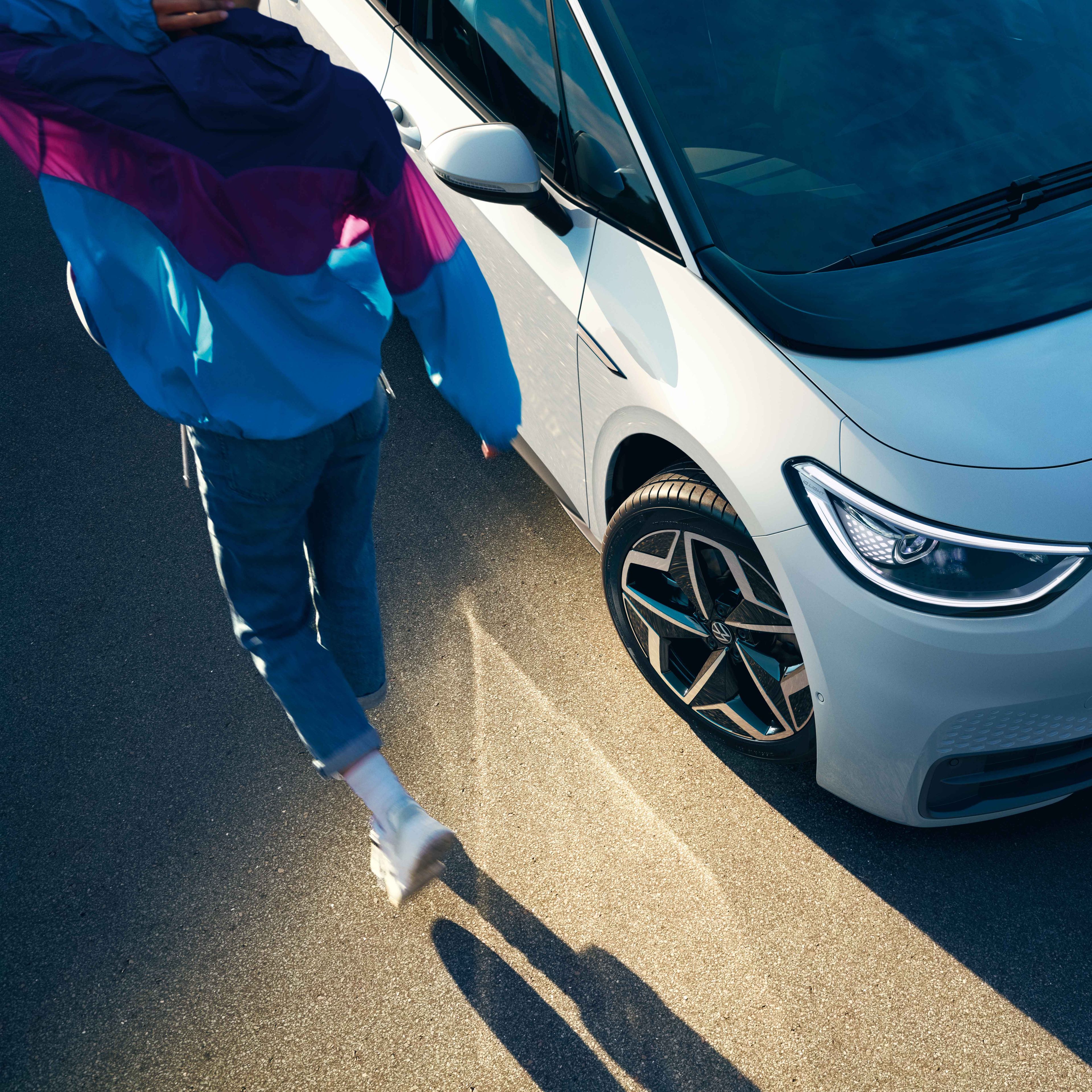 Zu sehen ist eine Frau die vor einem VW e-up! steht und diesen gerade auflädt. 