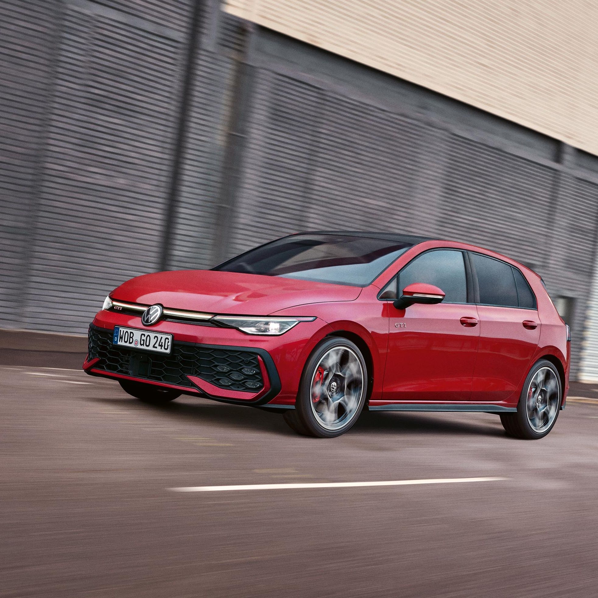 Червен Volkswagen Golf GTI Mk8, заснет в движение пред индустриална сграда