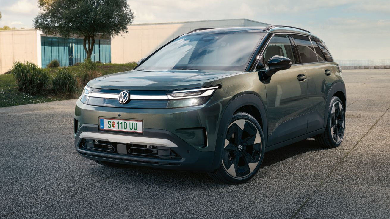 Зелен VW ID. Cross стои пред модерна стъклена сграда върху бетонна повърхност.