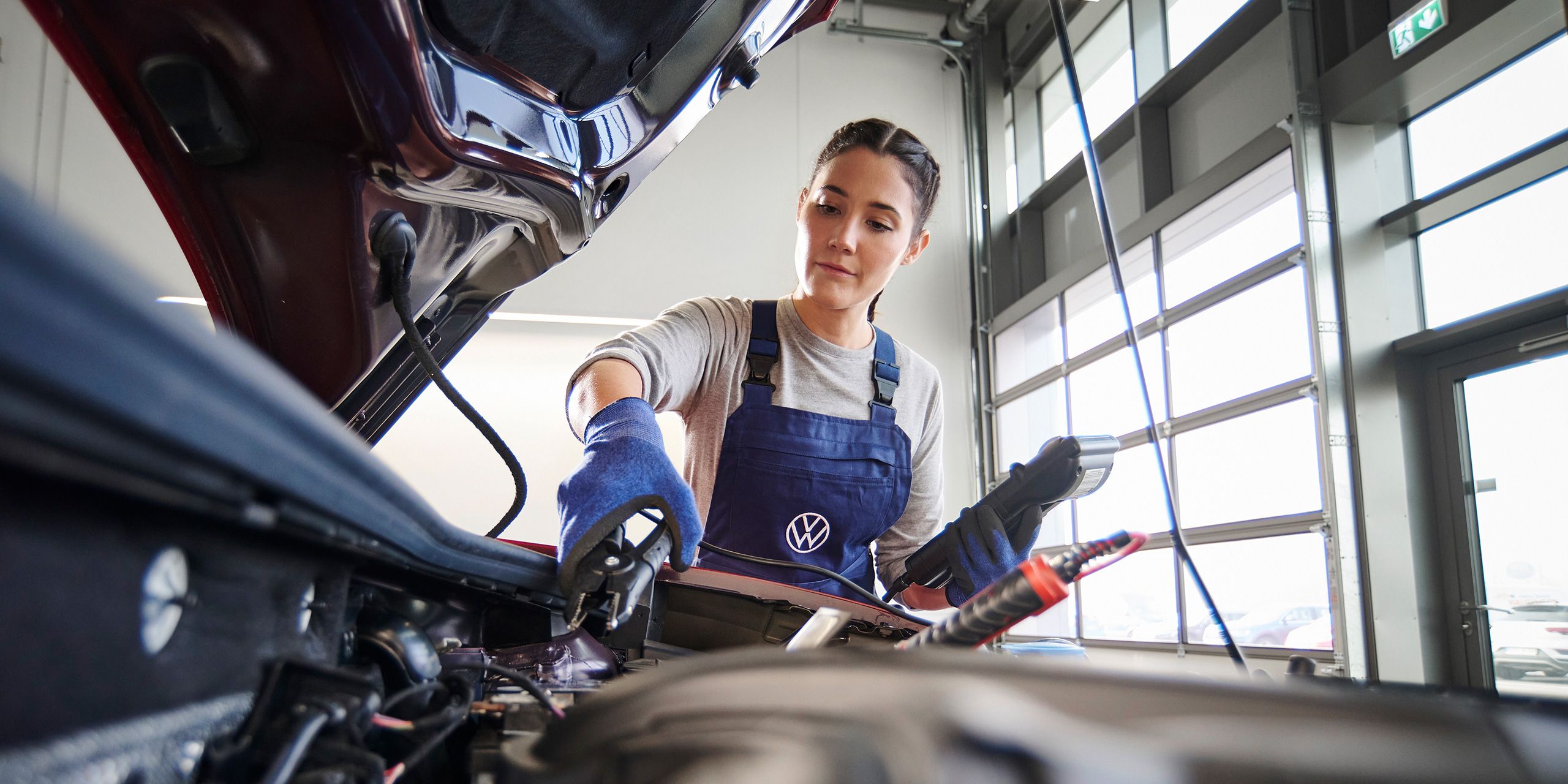 Eine Volkswagen Mechanikerin beim Funktionstest der Starterbatterie.