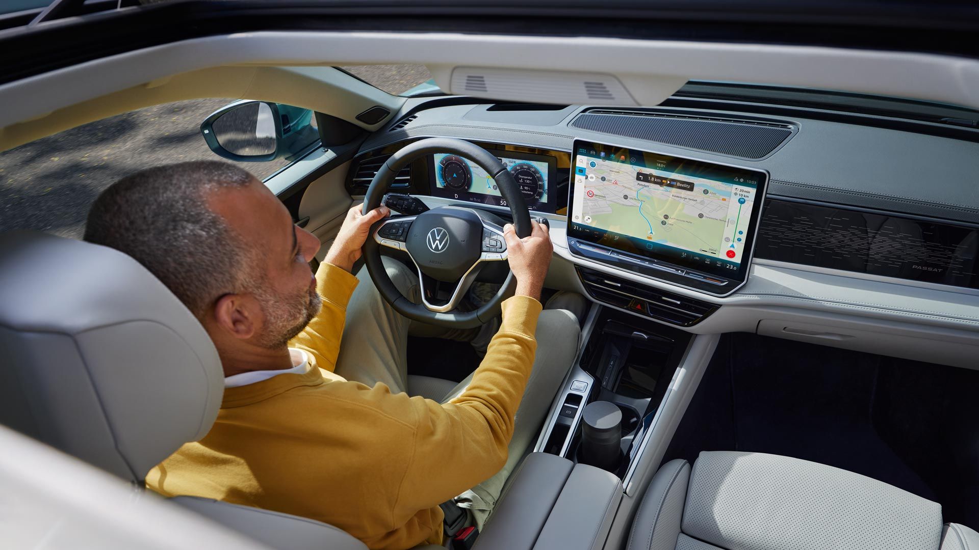 Поглед отгоре през отворения опционален шибедах на VW Passat, в който седи мъж с две ръце на волана.