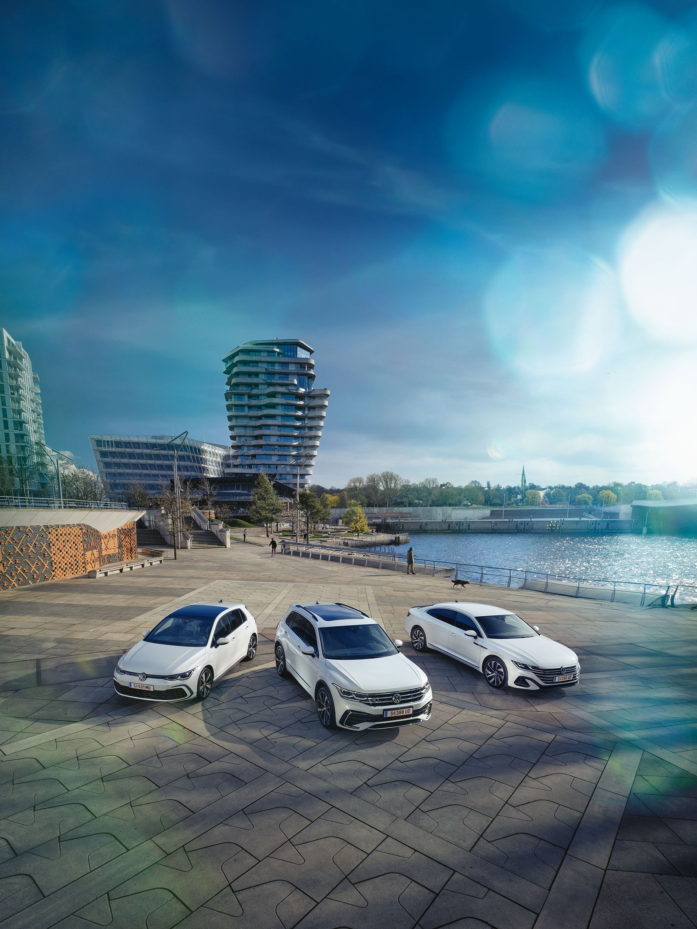 Drei weiße VW Lagerfahrzeuge parken am Hafen