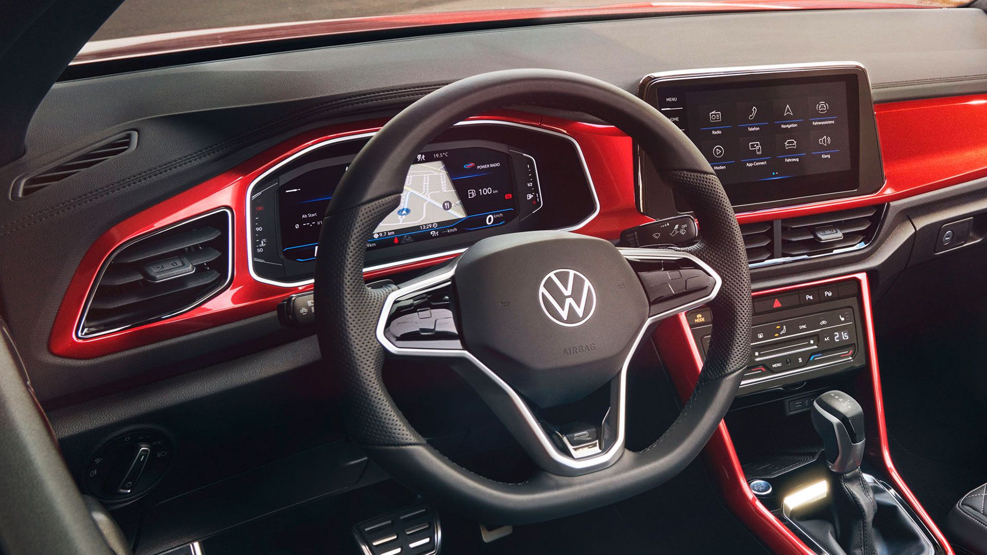 Поглед към кокпита на T-Roc Cabriolet в червен цвят с мултифункционален волан, радио и Digital Cockpit.