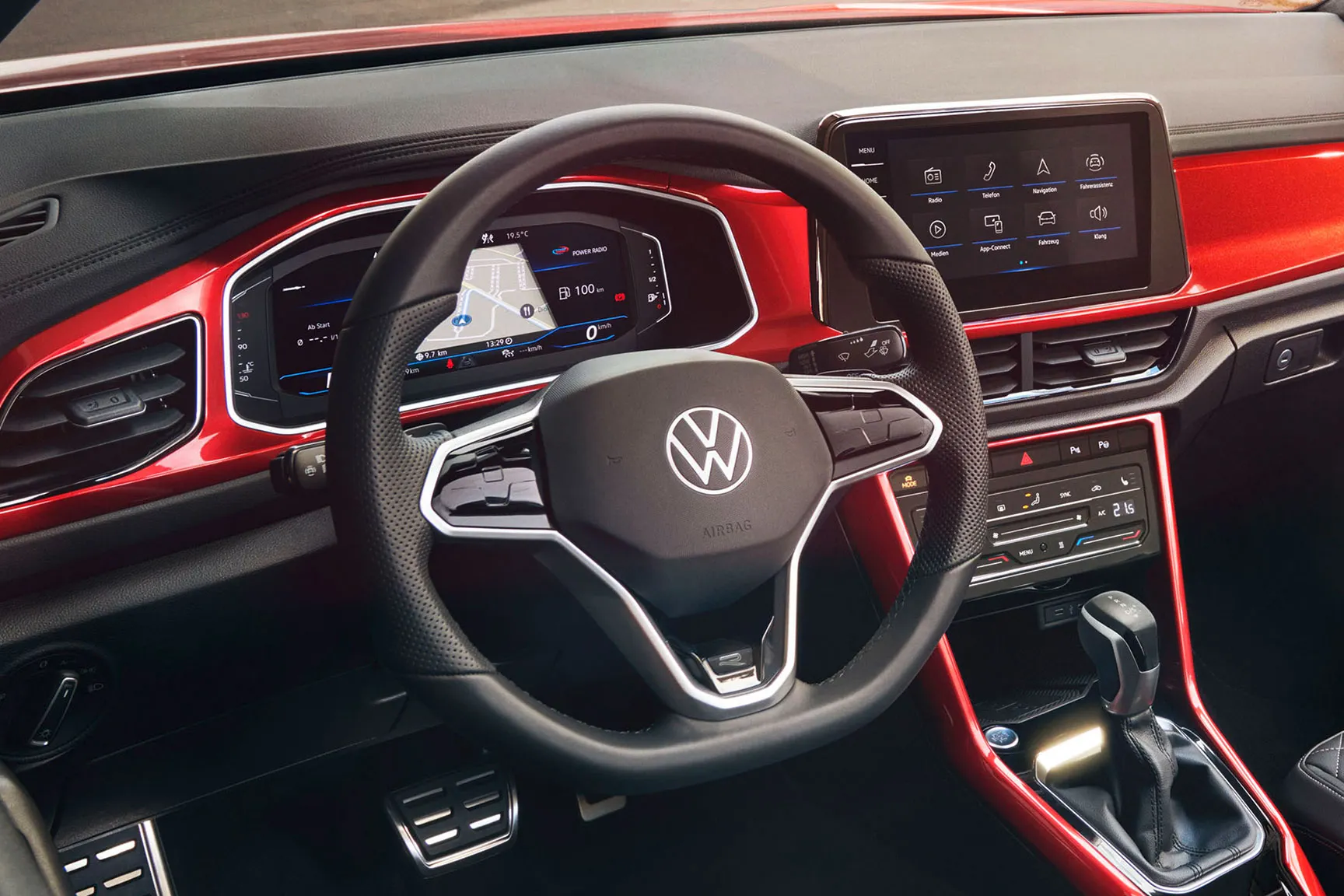 Поглед към кокпита на T-Roc Cabriolet в червен цвят с мултифункционален волан, радио и Digital Cockpit.