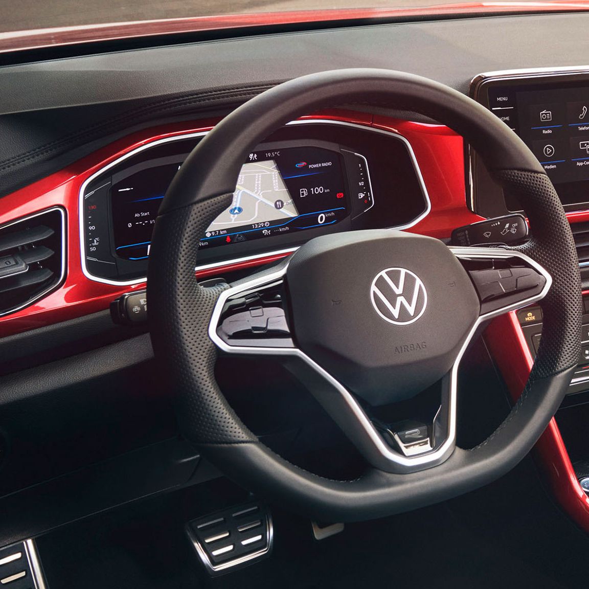 Поглед към кокпита на T-Roc Cabriolet в червен цвят с мултифункционален волан, радио и Digital Cockpit.