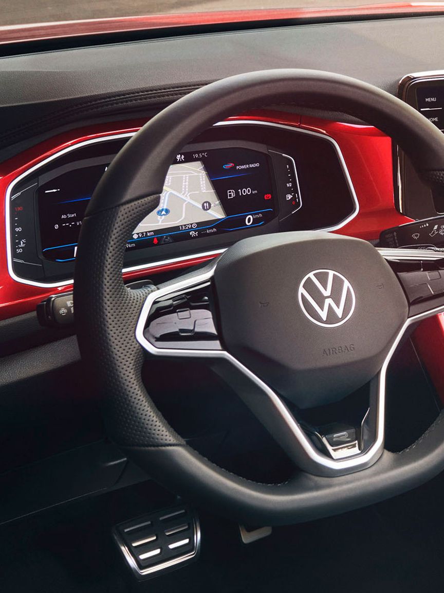 Поглед към кокпита на T-Roc Cabriolet в червен цвят с мултифункционален волан, радио и Digital Cockpit.