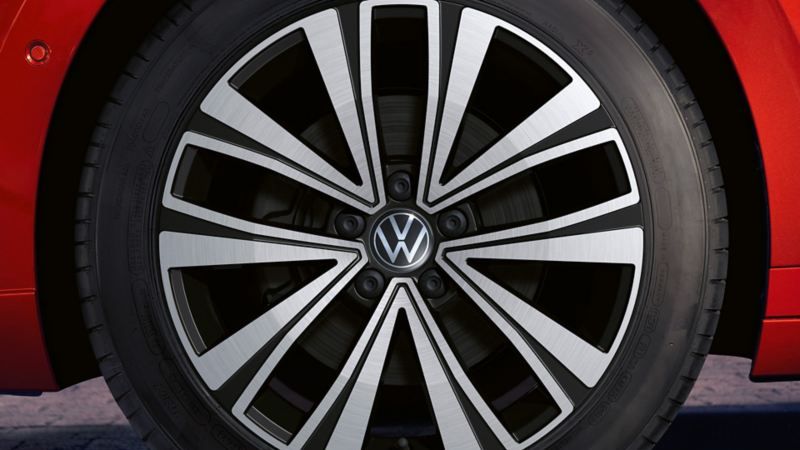 Близък план на алуминиева джанта с емблема Volkswagen на червен Arteon Shooting Brake