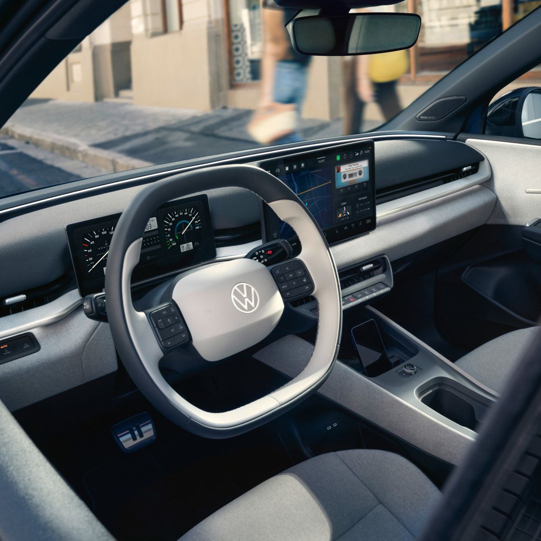Изглед през отворената врата на шофьора към кокпита на VW ID. Polo Style, който е паркиран край пътя.