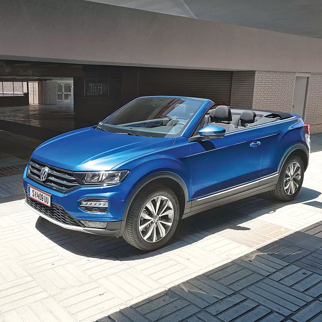 Син Volkswagen T-Roc кабриолет, паркиран под модерен навес с отворен покрив.