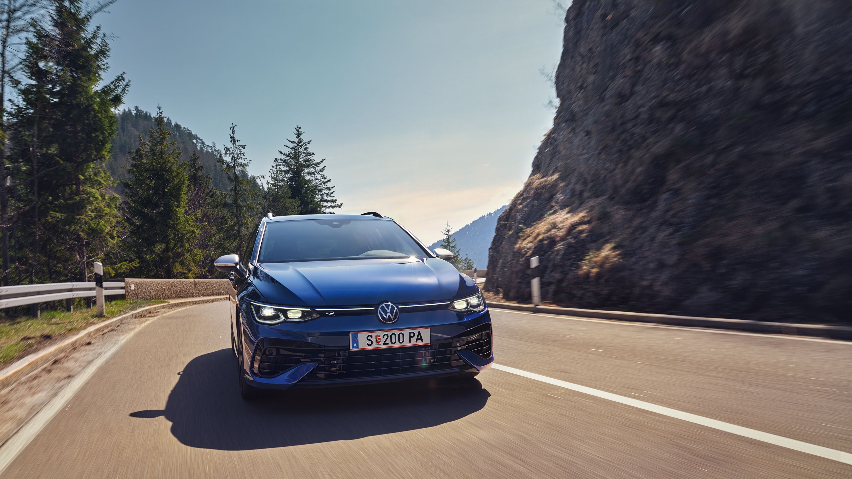 Син Volkswagen Golf Variant R в движение по планински път с динамичен завой