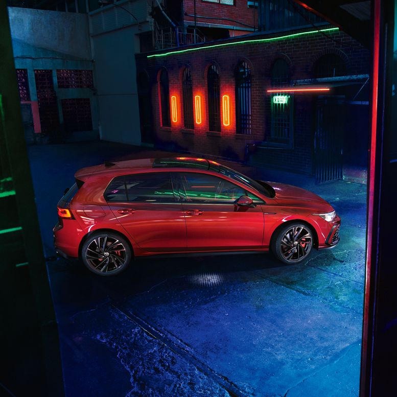 Червен Volkswagen Golf GTI, заснет отстрани в индустриална обстановка с ефектно неоново осветление
