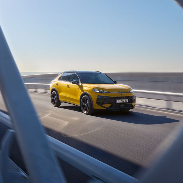 Жълт Volkswagen T-Roc в движение по мост при слънчево време