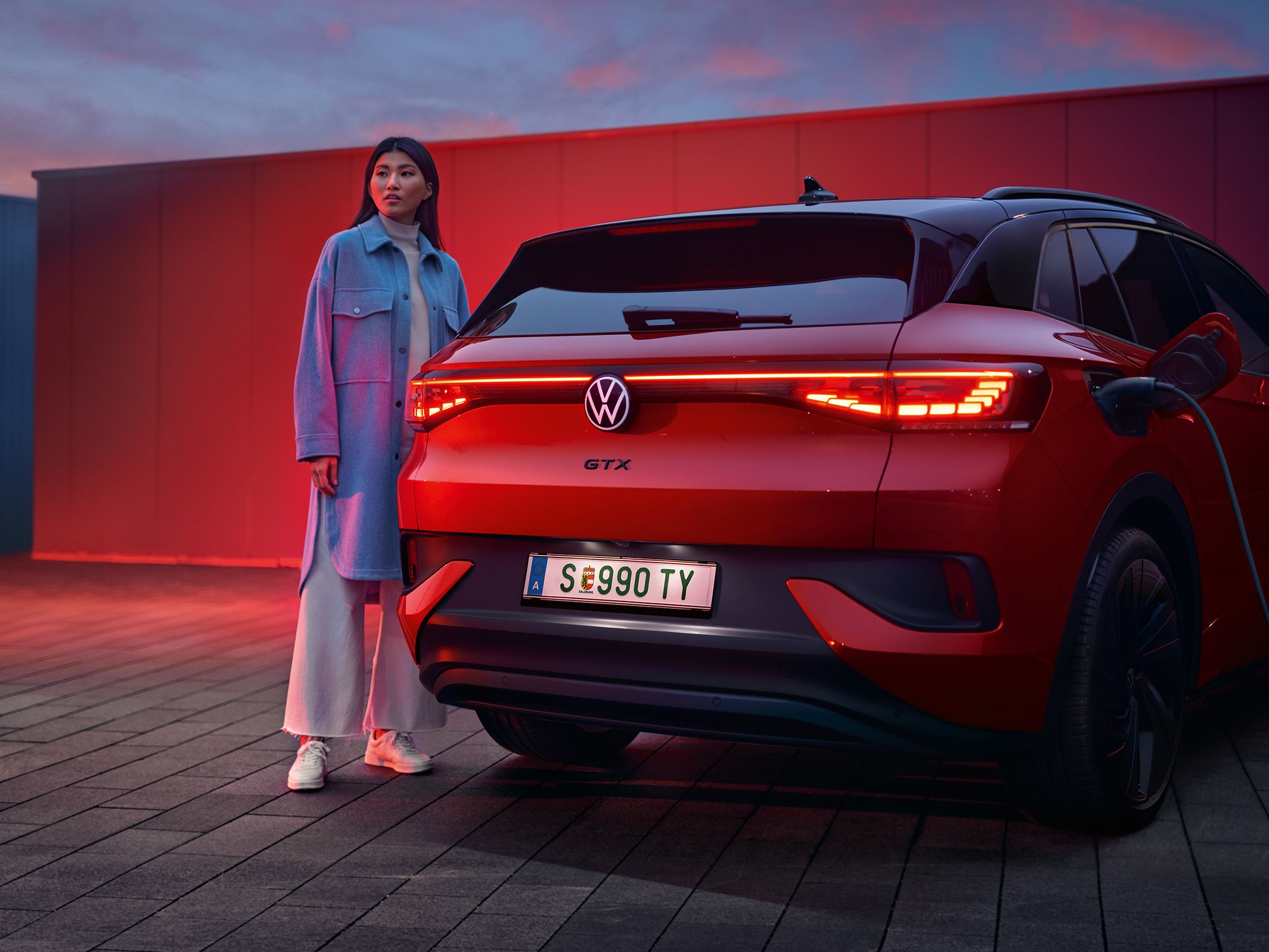 Изглед отзад на VW ID.4 GTX 4MOTION със стояща до него жена