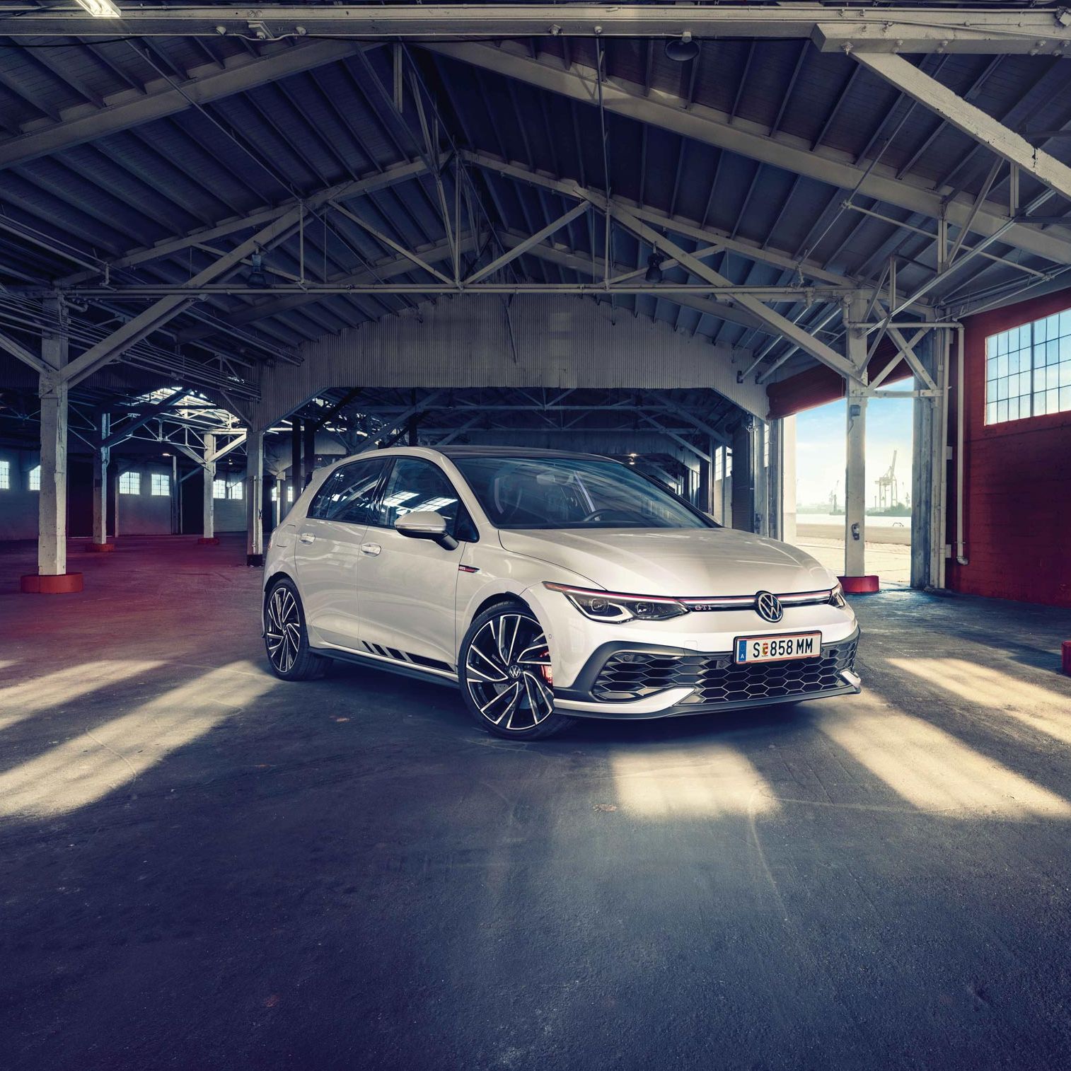 Бял Volkswagen Golf GTI, заснет отпред в индустриално хале с падаща естествена светлина