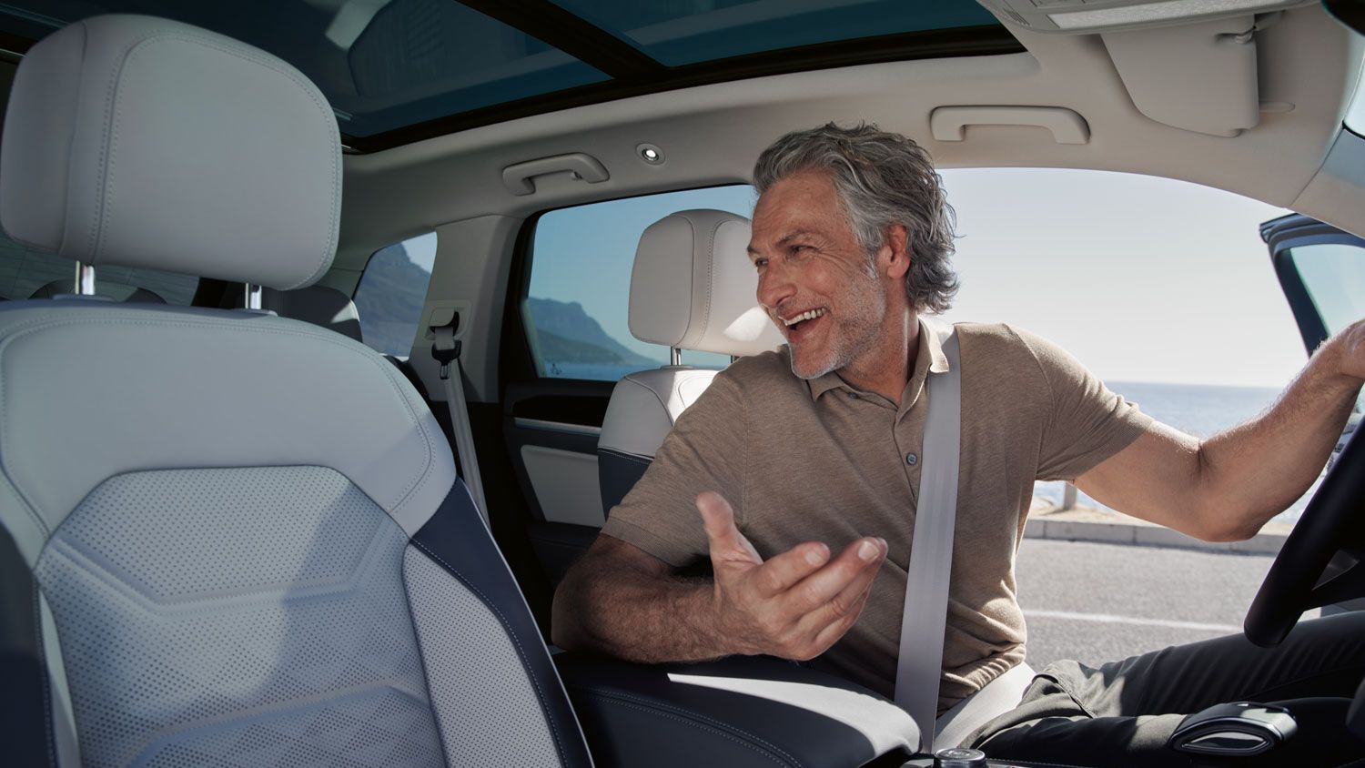 Мъж на предната седалка на паркиран VW Touareg Elegance разговаря с пътник на задната седалка.