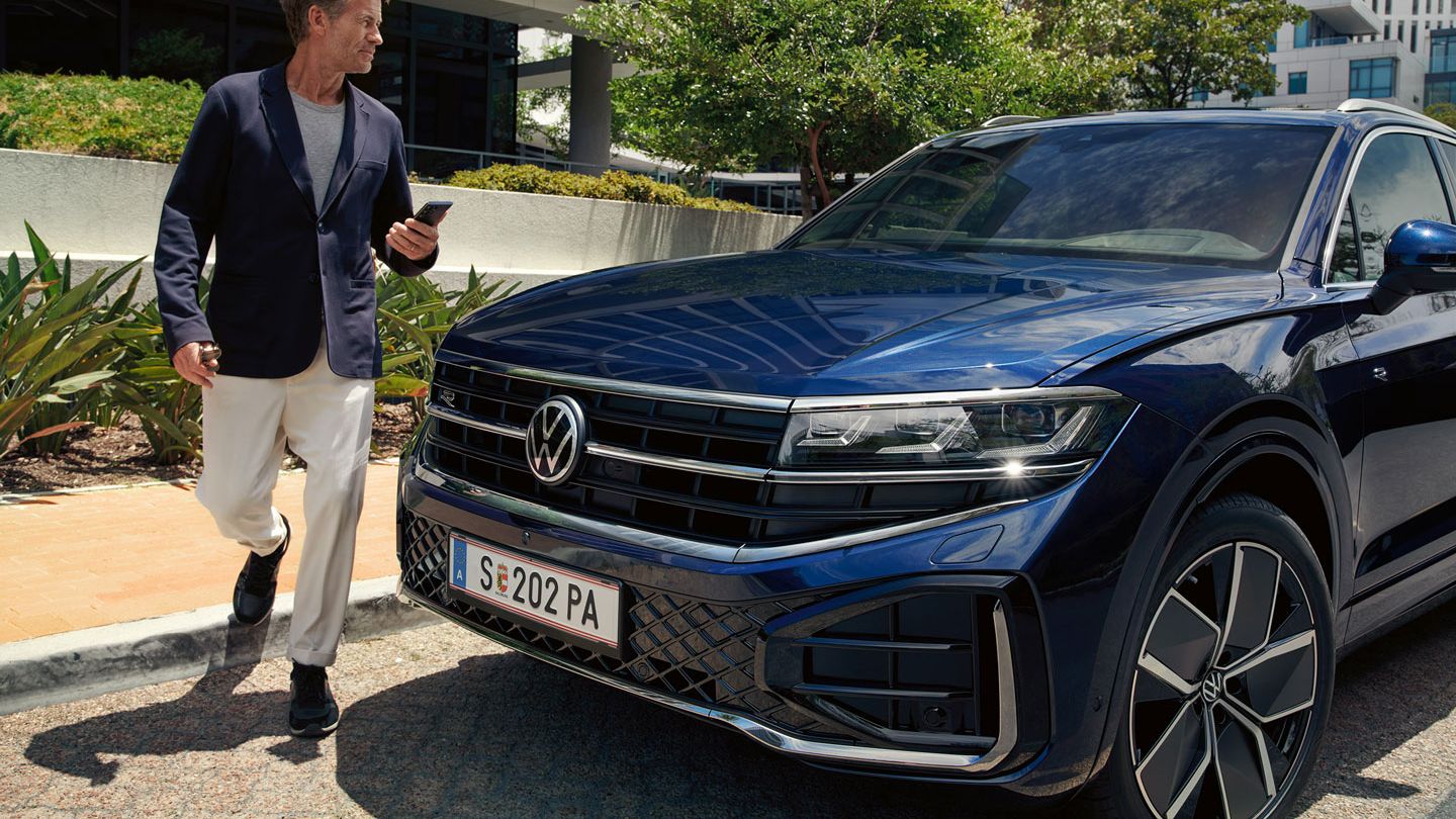 Мъж минава покрай паркиран VW Touareg R-Line.