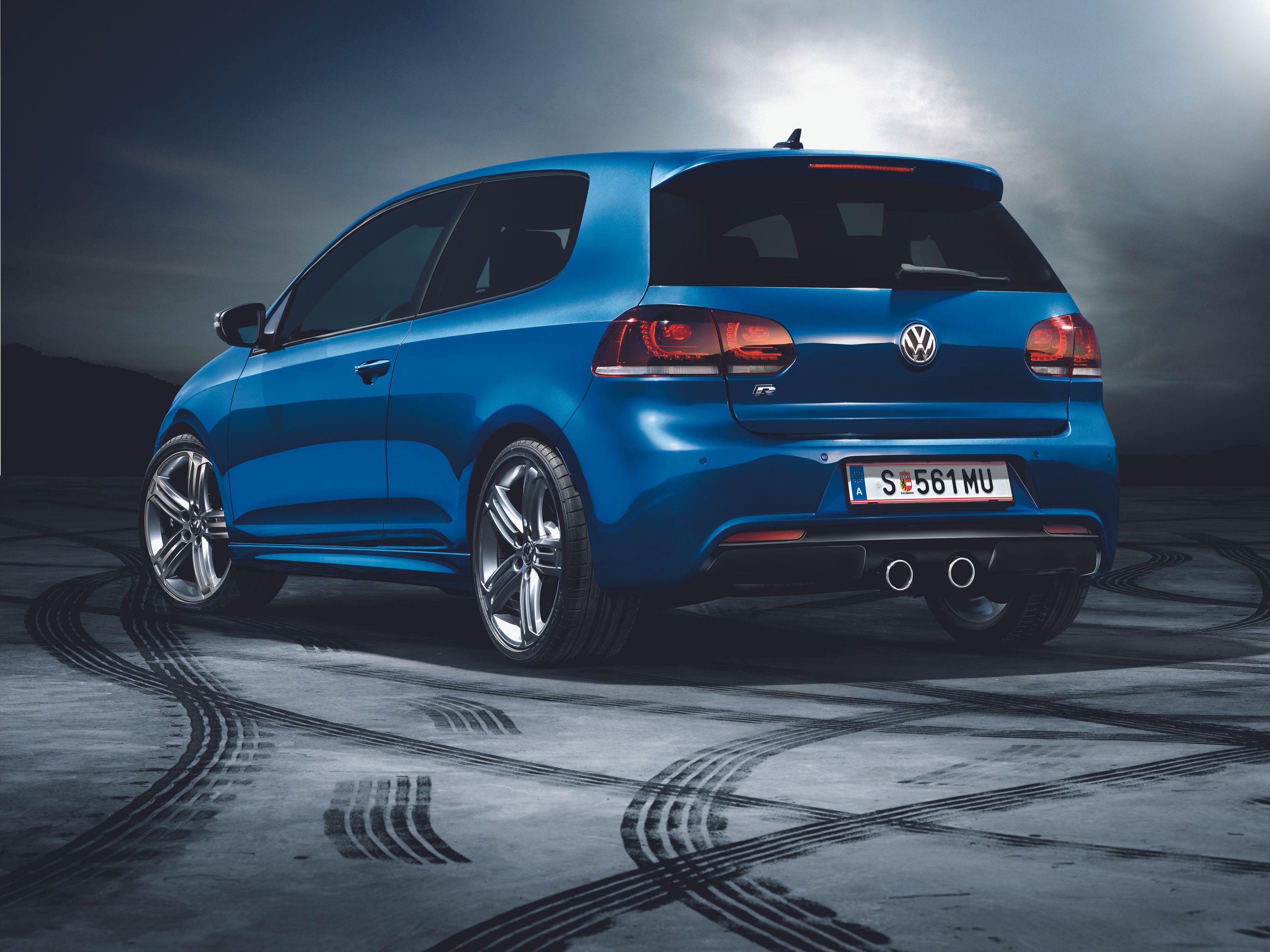 Син Volkswagen Golf R, заснет отзад върху асфалт с следи от гуми, подчертаващ спортния дизайн и двойната изпускателна система