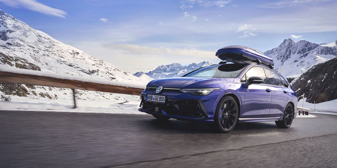 Син Volkswagen Golf R Variant с багажник на покрива, в движение по планински път сред сняг.