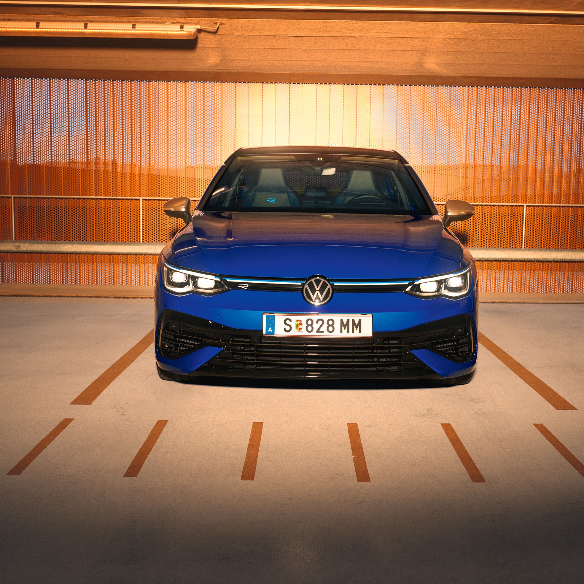 Син Volkswagen Golf R, заснет отпред на паркинг с оранжеви акценти